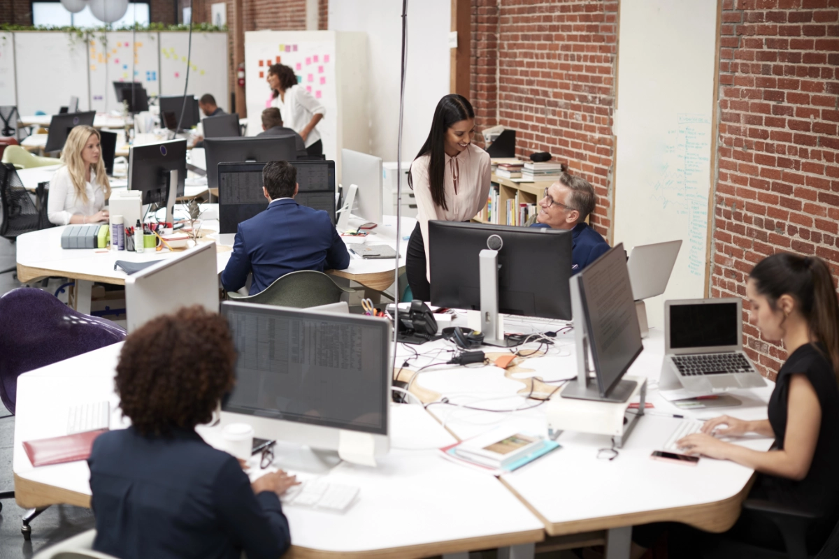 Een groep professionals die in een kantoortuin met diverse groepen bureaus werkt.